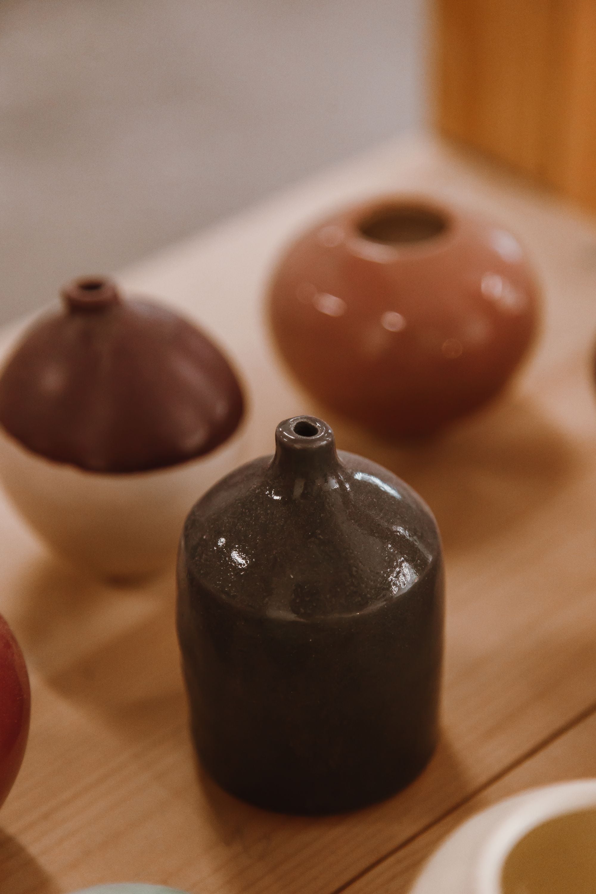Trois petits vases émaillés bruns, roux et ivoire sur du bois.