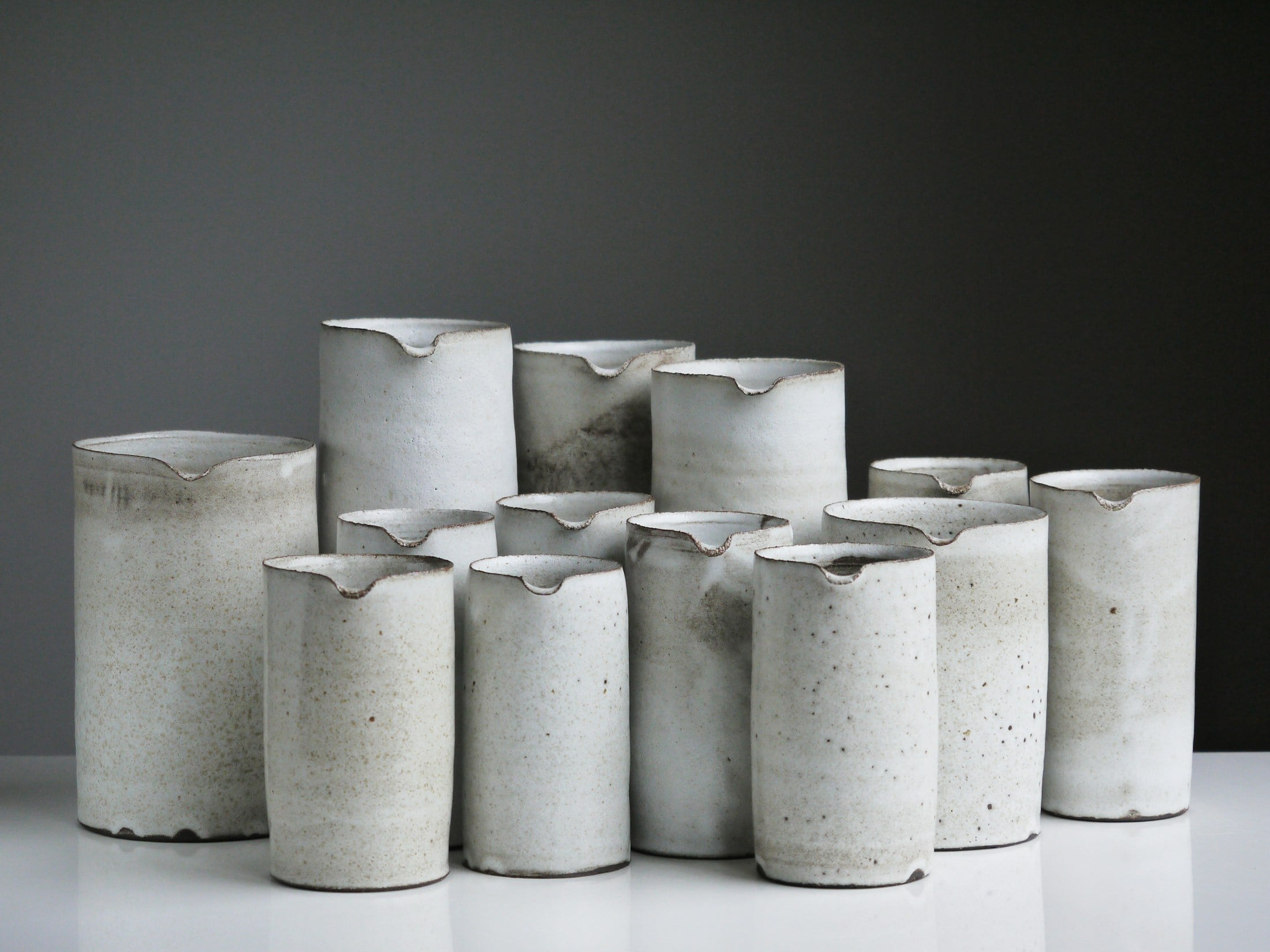 Un ensemble de verseuses cylindriques en céramique ivoire.